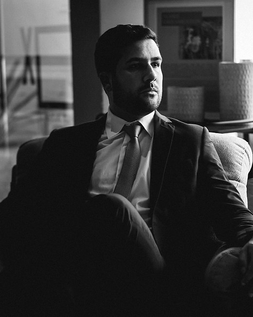 Renan Alonso Barreto, advogado, sentado no escritório, em retrato em preto e branco.
